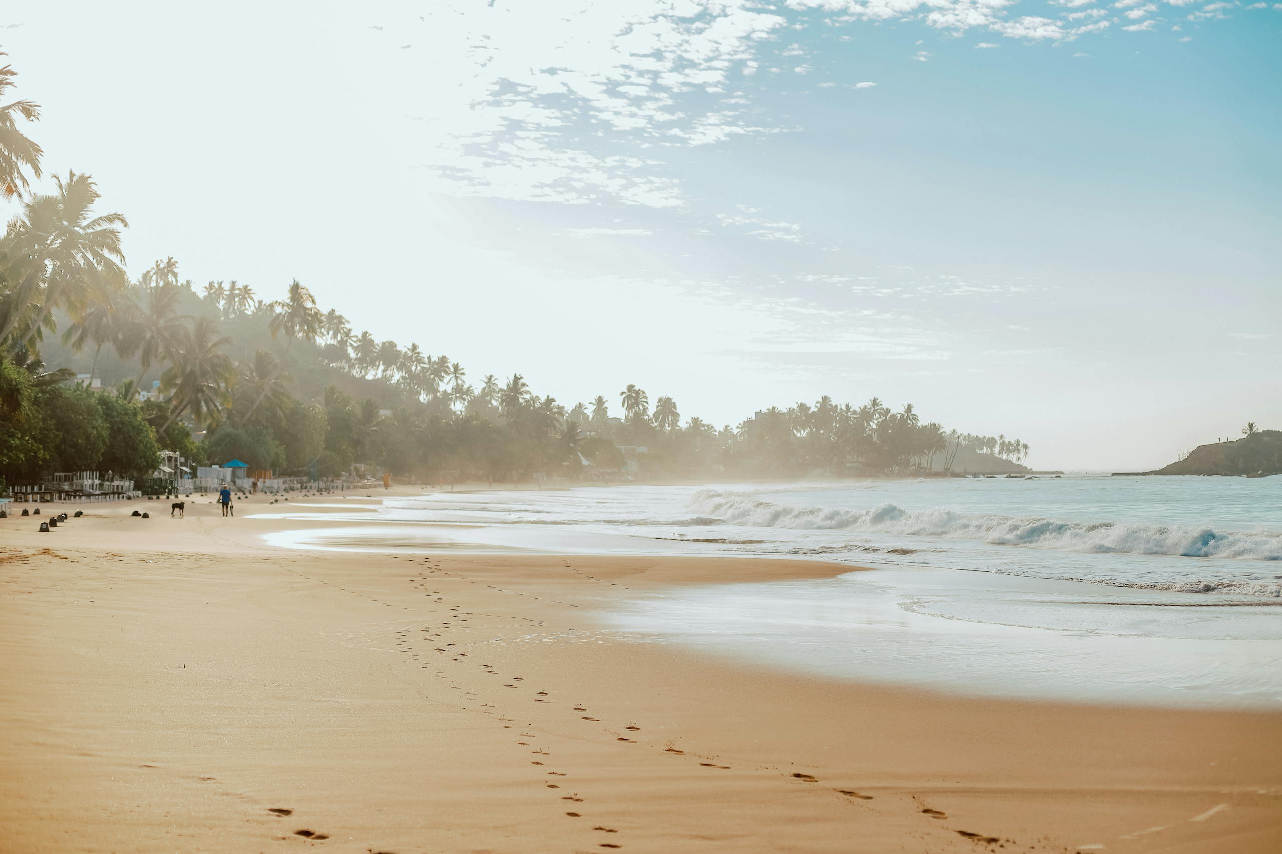 Footprints in the sand on a tranquil beach in Mirissa, Sri Lanka at sunrise.